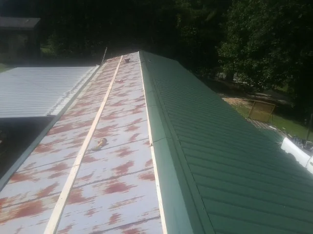 Old rusted panels beside newly installed green metal roofing — Wind Damage Roof Repair by Roofing Brothers in Maple Falls