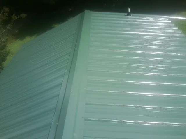 New green metal panels meeting at the ridge of a roof — Flat Roof Repair work by our crew in Maple Falls