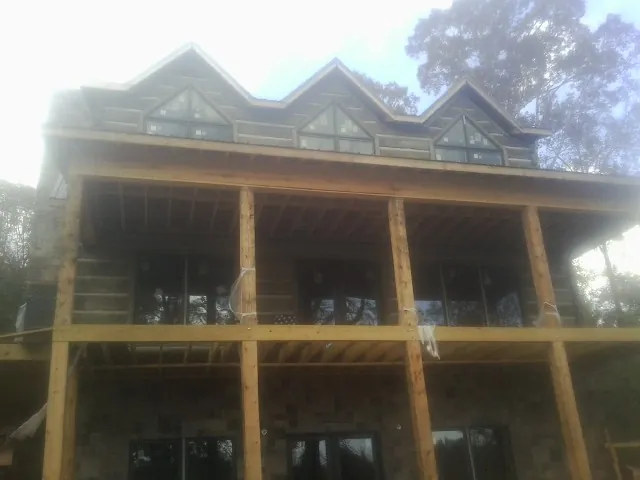 Dormers and porch framing on a large log home under construction — Roof Coating work by our crew in Maple Falls