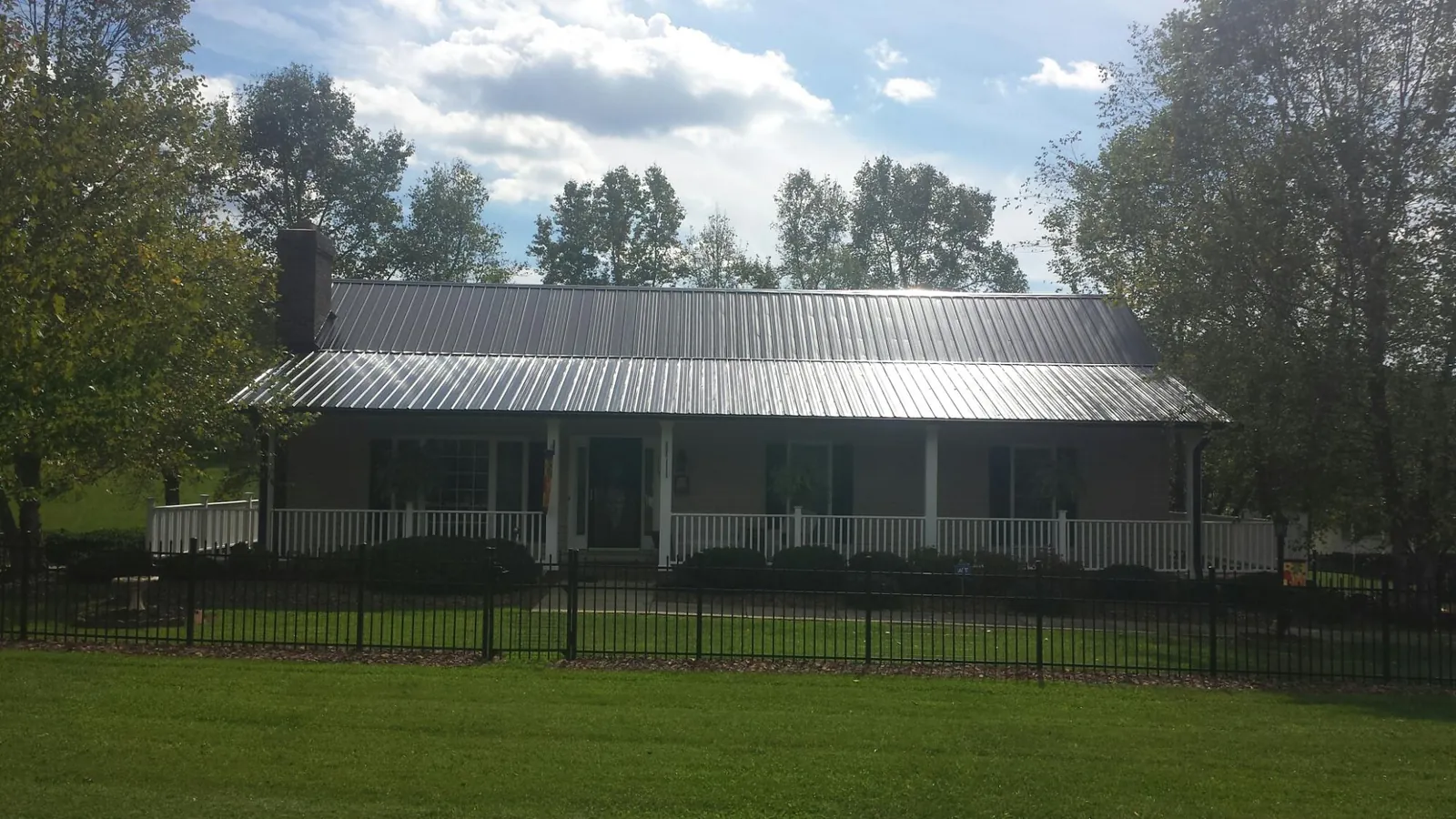 Gray metal roof on a brick ranch with a full width front porch — Gutter Guard Installation work by our crew in Maple Falls