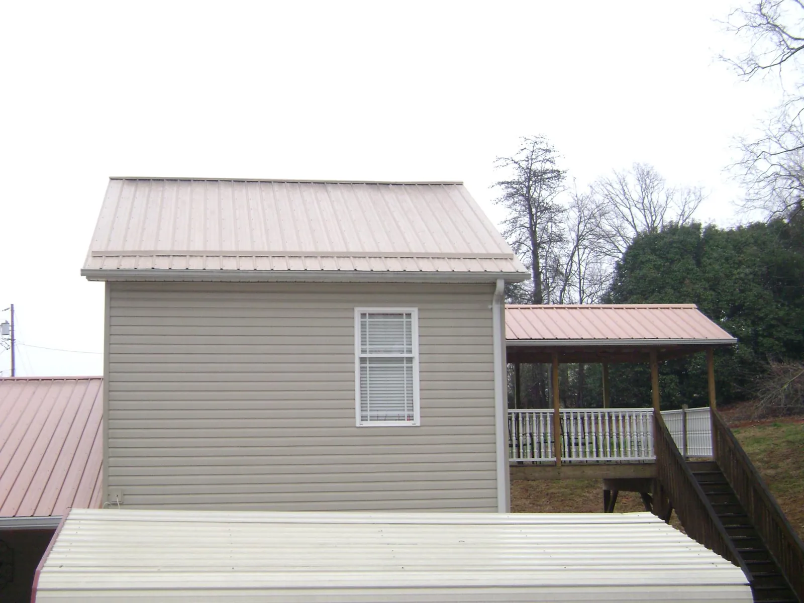 Tan metal roofs on a two story addition and attached porch, from a Roof Replacement job in Maple Falls