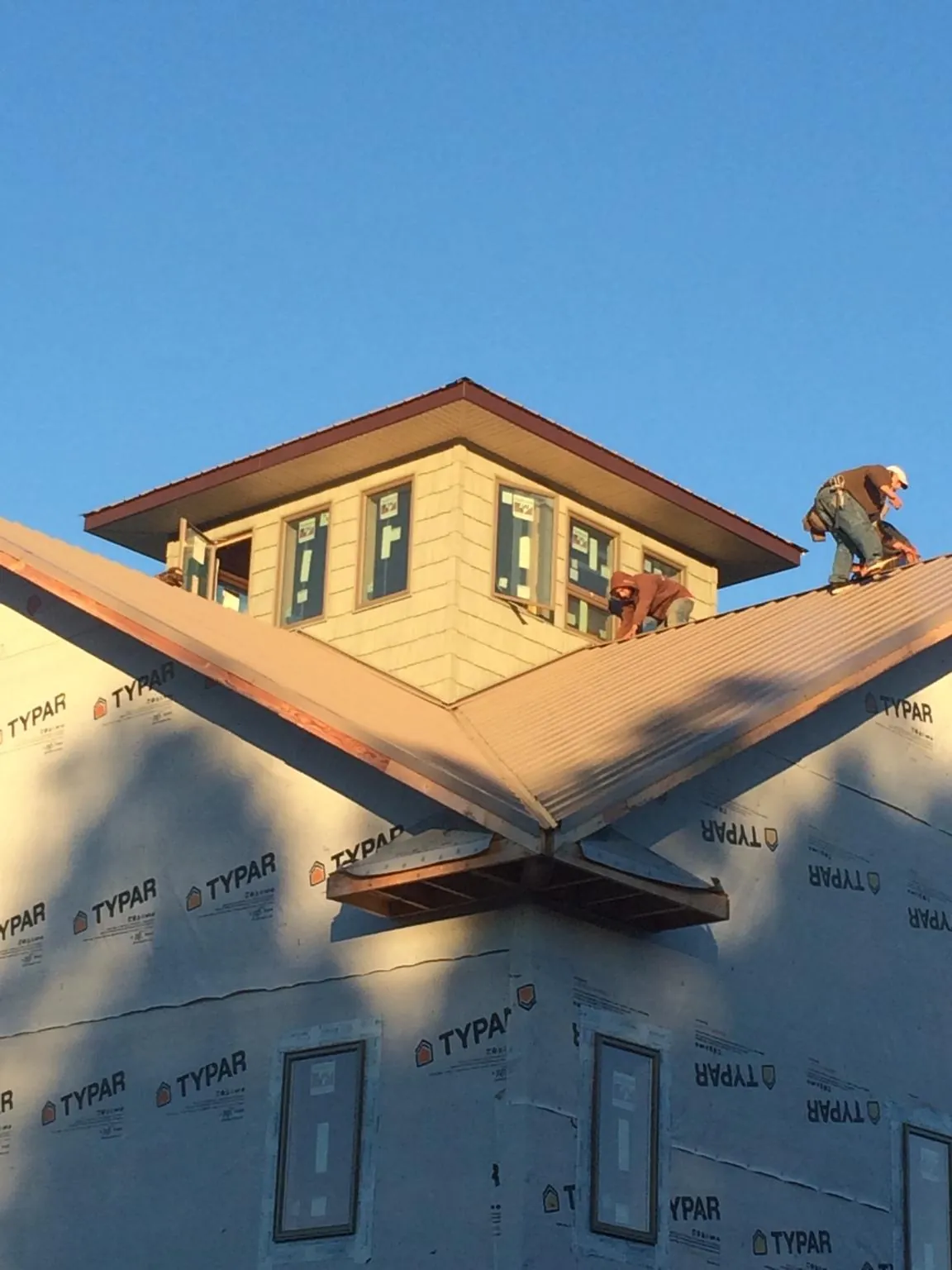 Roofers working around a rooftop cupola on a new metal roof at sunset — Roof Waterproofing in Maple Falls by Roofing Brothers